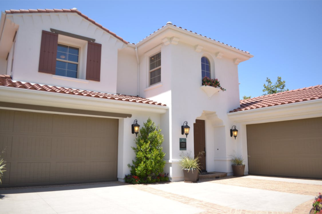 A white Spanish-style Austin home featuring professionally maintained overhead doors by a local garage door repair Austin TX specialist.